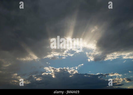 Wolken mit Sonnenstrahlen nach einem späten Nachmittag Regen Sturm durchschimmern. Stockfoto