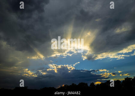 Wolken mit Sonnenstrahlen nach einem späten Nachmittag Regen Sturm durchschimmern. Stockfoto