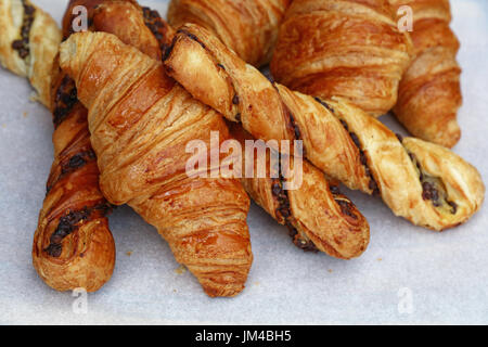 Frisch gebackene golden braun französischen Croissants und Blätterteig Blätterteig auf weißem Papier Pergament im Einzelhandel Bäckerei Anzeige speichern, Nahaufnahme, hoher Winkel Stockfoto