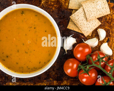 Schüssel mit Karotte und Koriander Suppe gegen einen Aufgeregten verbrannt Backofen oder Backblech Stockfoto