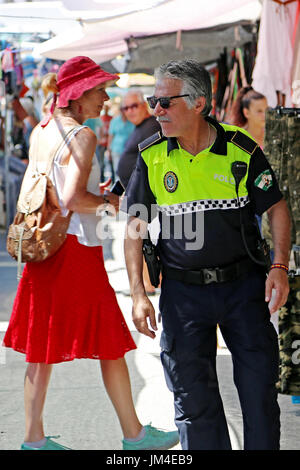 Ein lokaler Polizist patrouilliert einen Straßenmarkt in Nerja, Andalusien, Spanien, Costa Del Sol, Mittelmeer Stockfoto