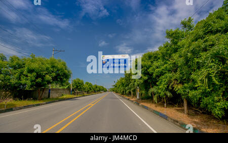 Esmeraldas, Ecuador - 16. März 2016: Asphaltierte Straße an der Küste, mit informativen Schild, umgeben mit Abundat Vegetation an einem sonnigen Tag in der ecuadorianischen Küste Stockfoto