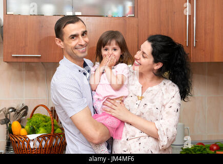 Familienbild in Küche Interieur mit frischem Obst und Gemüse, gesunde Ernährung Konzept, schwangere Frau, Mann und Kind Mädchen Stockfoto