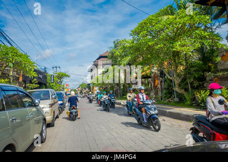 BALI, Indonesien - 5. April 2017: Motorradfahrer hinunter die Straße in Ubud, Bali Stockfoto