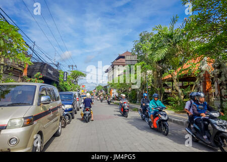 BALI, Indonesien - 5. April 2017: Motorradfahrer hinunter die Straße in Ubud, Bali Stockfoto