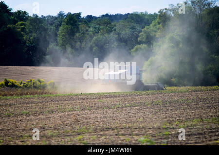 Ein grau kombinieren Ernte ein Feld mit einem wehenden Staub hinter sich. Stockfoto