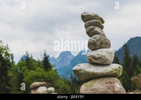 Steinen Gleichgewicht, Hierarchie-Stack über bewölktem Himmel in Bergen. Inspirierende Stabilität Konzept auf Felsen.