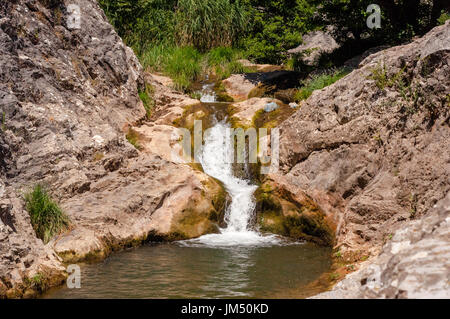 Kleiner Wasserfall läuft durch felsiges Gelände Stockfoto