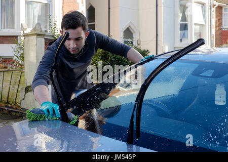 Junger Mann mit seinem Auto Reinigung mit Hochdruckreiniger und schwamm England Großbritannien Stockfoto