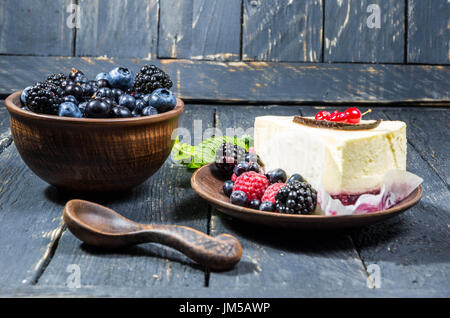 Eine Schale mit Beeren und einen Käsekuchen. Bunte Beeren. Süße Waldbeeren. Stockfoto