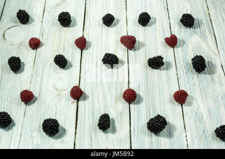 Brombeeren und Himbeeren. in einer Reihe angeordnet sind. Ansicht von oben. Beeren auf einem weißen Hintergrund. Stockfoto