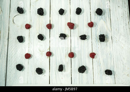 Brombeeren und Himbeeren. in einer Reihe angeordnet sind. Flach zu legen. Beeren auf einem weißen Hintergrund. Stockfoto