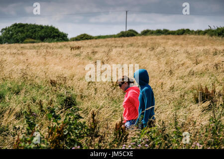 Zwei junge Frauen in Hoodies Wandern in Felder an Bempton Klippen RSPB Reserve, UK. Eine Frau hat ihre Kapuze, Kapuzenjacke Hoodie. Stockfoto