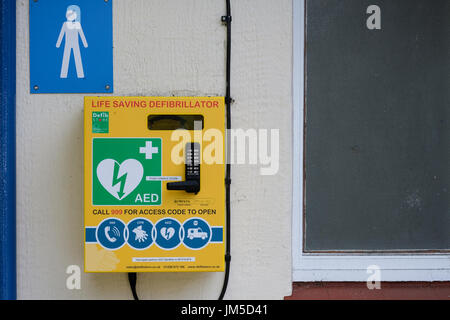 Defibrillator montiert an der Wand eines männlichen öffentlichen connvenience Toilette in Harrogate, North Yorkshire, England, UK. Stockfoto