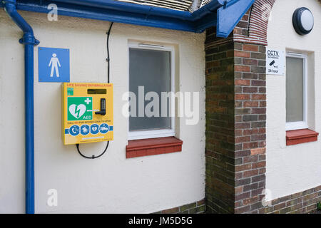 Defibrillator montiert an der Wand eines männlichen öffentlichen connvenience Toilette in Harrogate, North Yorkshire, England, UK. Stockfoto