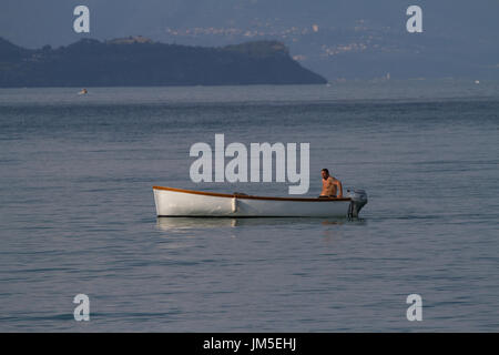 Mann in kleinen offenen Boot mit Außenbordmotor. Am Gardasee. Italien Stockfoto