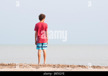 13 Jahre alte Junge stand an einem Strand, Blick auf einen See Stockfoto