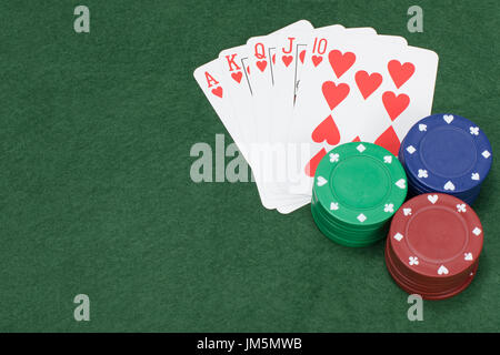 Poker chips blau grün und rot auf Filz bedeckt Tisch neben fünf Spielkarten Stockfoto