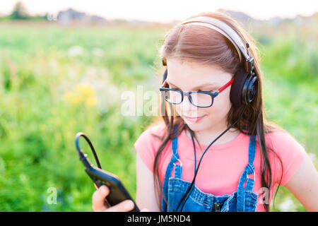 Teengirl Musikhören mit ihrem retro Vintage Kopfhörer im freien Stockfoto