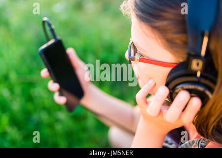 Teengirl Musikhören mit ihrem retro Vintage Kopfhörer im freien Stockfoto