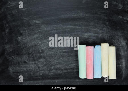 Sticks von farbiger Kreide ordentlich hintereinander in der Ecke auf einer Kreidetafel mit textfreiraum und Textur angeordnet Stockfoto