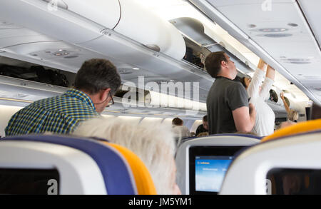 München, Deutschland - 16. Juli 2017: Die Passagiere sind aus Ihrem Gepäck aus der Overhead Fahrgastraum eines Airbus 330 - 300, Lufthansa Airlines. Stockfoto