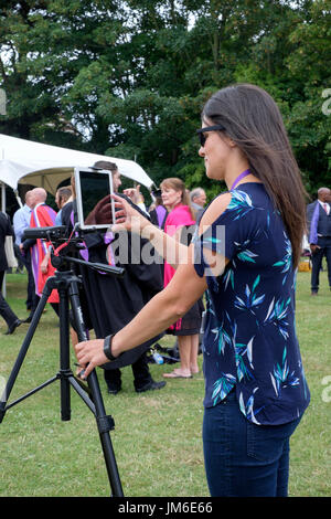 Junge Frau fotografieren und Video über ein i-Pad auf einem Stativ bei einer Abschlussfeier in Portsmouth, England uk montiert Stockfoto