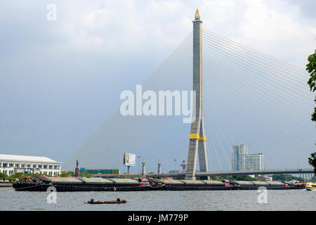 Ein Lastkahn gleitet unter Rama VIII Schrägseilbrücke über den Chao Phraya River, Bangkok, Thailand. Stockfoto