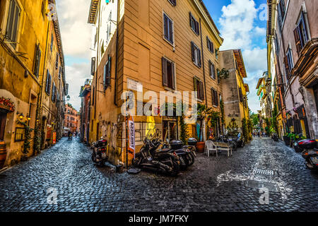 Malerischen und bunten Seitenstraße mit Motorrädern und Geschäfte in Trastevere Viertel von Rom Italien an einem sonnigen Sommernachmittag Stockfoto