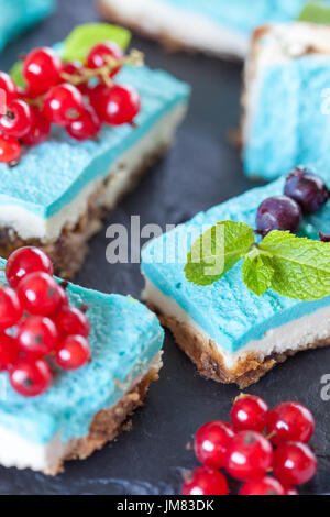 Blaue vegane Scheiben Käsekuchen mit Beeren. Liebe für eine gesunde vegane Ernährung Konzept. Stockfoto