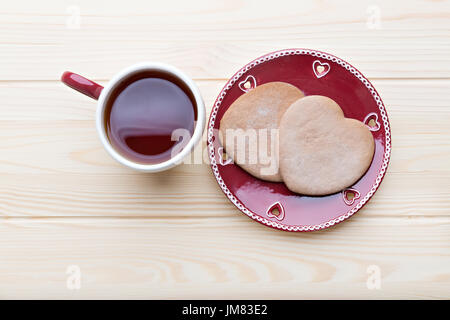 Lebkuchen auf die rote Platte und heißen Tee auf dem Holztisch. Stockfoto