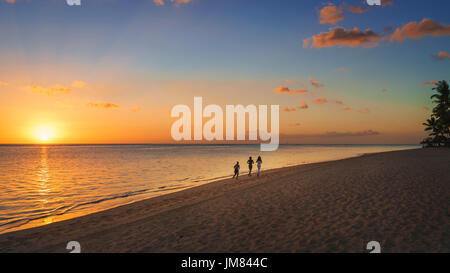 Thtree Silhouette laufen am Strand bei Sonnenuntergang in Mauritius. Stockfoto