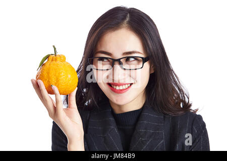 junge asiatische Geschäftsmann hält eine Ugli Obst, glücklich und lächelnd, Studio gedreht, auf weißem Hintergrund isoliert. Stockfoto