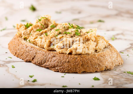 Eine Scheibe Vollkornbrot mit Huhn zu verbreiten und Kräutern Stockfoto