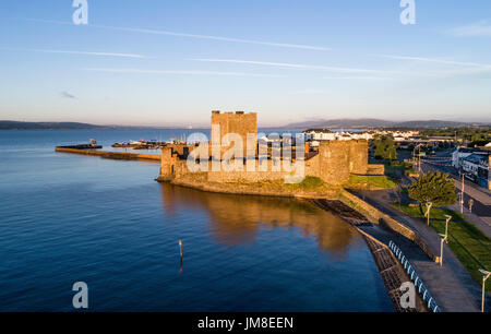 Norman Mittelalterburg in Carrickfergus in der Nähe von Belfast, Nordirland. Luftbild bei Sonnenaufgang mit weit Blick auf Belfast im Hintergrund. Stockfoto