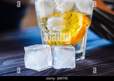 Alkoholisches Getränk mit Zitrone und Eis in einem Glas auf einem alten dunklen Holztisch. Nahaufnahme des kaltes Getränk Stockfoto