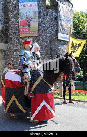 Besucher sahen ein großes Spektakel, wenn Schauspieler in mittelalterlichen Rüstungen auf Fuß und eines Pferdes am Arundel Castle gekämpft. Ein weiblicher Ritter zu Pferd am Eingang Stockfoto