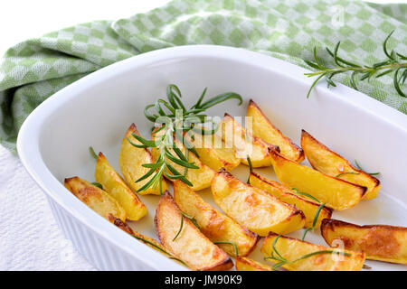 Gebackene Kartoffelspalten mit Rosmarin in eine Auflaufform Stockfoto
