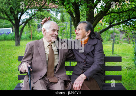 Niedliche 80 plus Jahre alt verheiratet Paar posieren für ein Porträt in ihrem Garten. Liebe für immer Konzept. Stockfoto