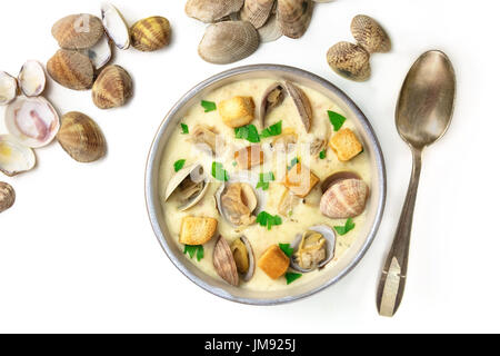 Ein Foto von einer Schüssel Muschelsuppe, dekoriert mit frischer Petersilie und Croutons, mit Muschelschalen, geschossen von oben mit einem Löffel, auf weißem Hintergrund Stockfoto