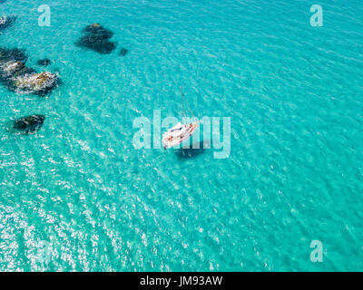 Luftaufnahme von einem festgemachten Boot schwimmt auf einem transparenten Meer. Tauchen Entspannung und Sommerferien. Italienischen Küsten, Strände und Felsen Stockfoto