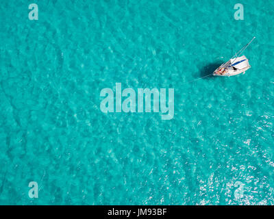 Luftaufnahme von einem festgemachten Boot schwimmt auf einem transparenten Meer. Tauchen Entspannung und Sommerferien. Italienischen Küsten, Strände und Felsen Stockfoto