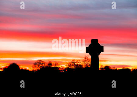 Durham Landschaft: ikonische Celtic Steinkreuz steht auf dem Friedhof an der Durham Kathedrale, County Durham bei Sonnenuntergang Silhouette gegen den Abendhimmel Stockfoto