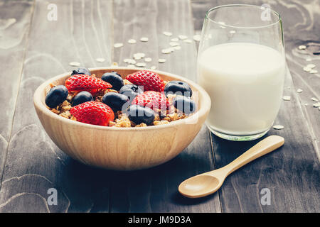 Hausgemachtem Müsli mit Erdbeeren und frischen Beeren auf Holztisch. Stockfoto