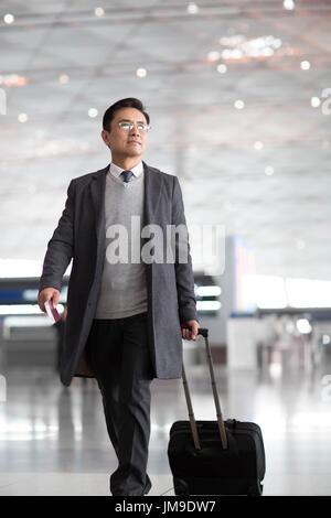 Chinesischer Unternehmer ziehen Rädern Gepäck im Flughafen-lobby Stockfoto