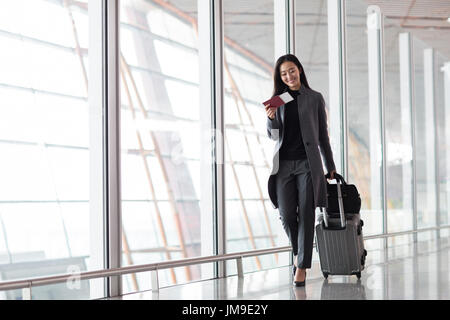 Chinesische Unternehmerin ziehen Rädern Gepäck im Flughafen-lobby Stockfoto