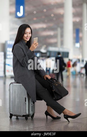 Chinesische Geschäftsfrau mit Rädern Gepäck im Flughafen-lobby Stockfoto