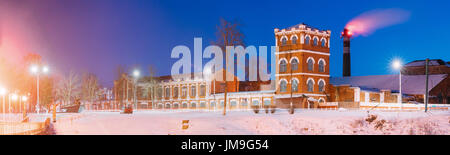 Dobrush, Region Gomel, Weißrussland. Panorama der alten Papier Fabrik Turm im Winter Abend oder Nacht. Historisches Erbe. Lunatscharski Avenue. Ampel Stockfoto