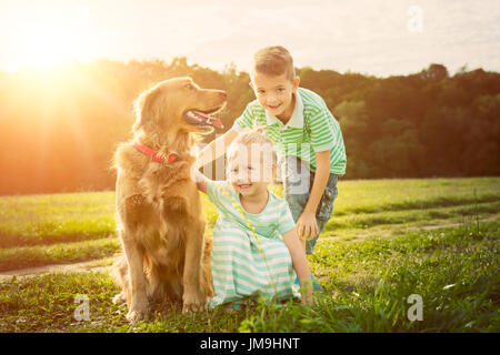 Entzückende Bruder und Schwester, die das Spiel mit Hund Stockfoto