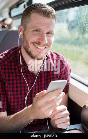 Junger Mann anhören von Musik auf dem Handy während der Fahrt zur Arbeit